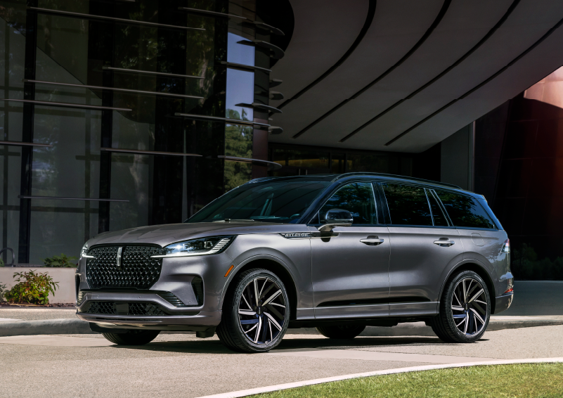 A gray 2025 Lincoln Aviator® SUV is parked outside a modern building showcasing the driver’s side of the vehicle. | Dan Cummins Lincoln in Nicholasville KY
