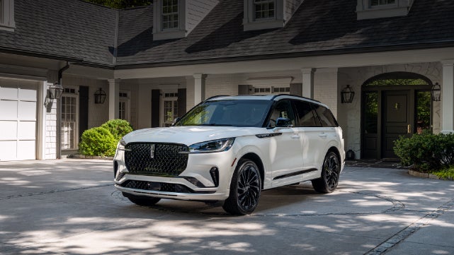 A white 2026 Lincoln Aviator® SUV is parked in the driveway of a luxury home. | Dan Cummins Lincoln in Nicholasville KY