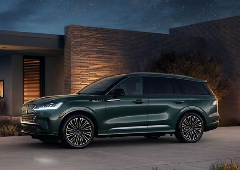 A green 2027 Lincoln Aviator® SUV is parked outside a contemporary home. | Dan Cummins Lincoln in Nicholasville KY