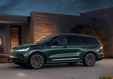 A green 2027 Lincoln Aviator® SUV is parked outside a contemporary home. | Dan Cummins Lincoln in Nicholasville KY