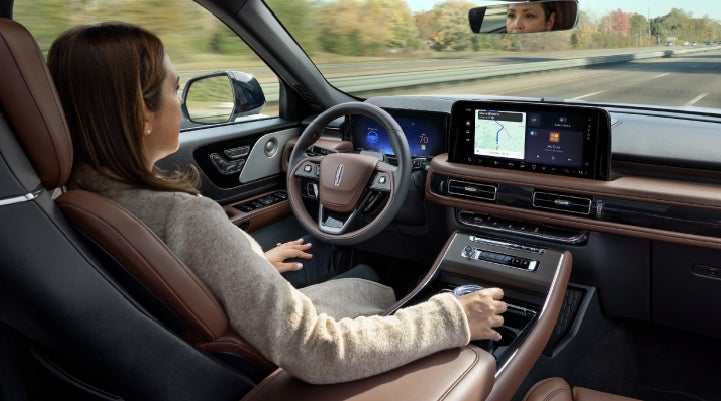 A 2027 Lincoln Aviator® SUV is being driven hands-free on a highway lined with trees. | Dan Cummins Lincoln in Nicholasville KY